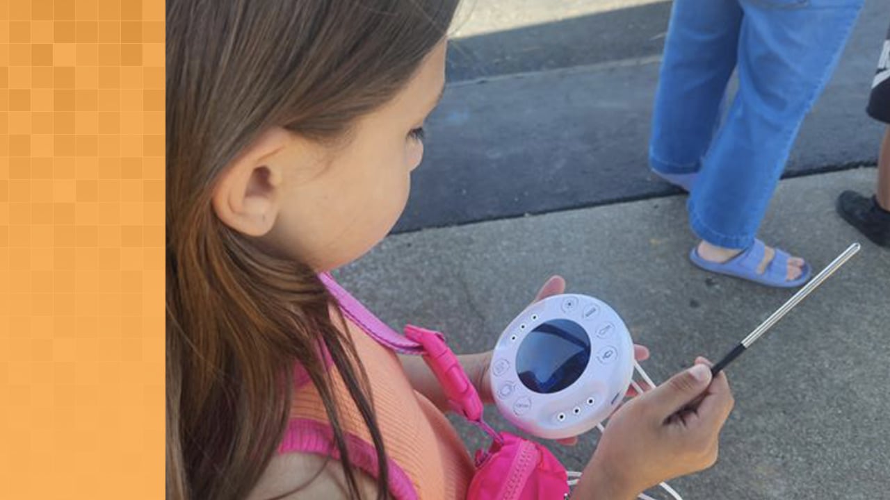 Young student holding an Xploris and looking at data on screen. Also holding a temperature measurement tool.