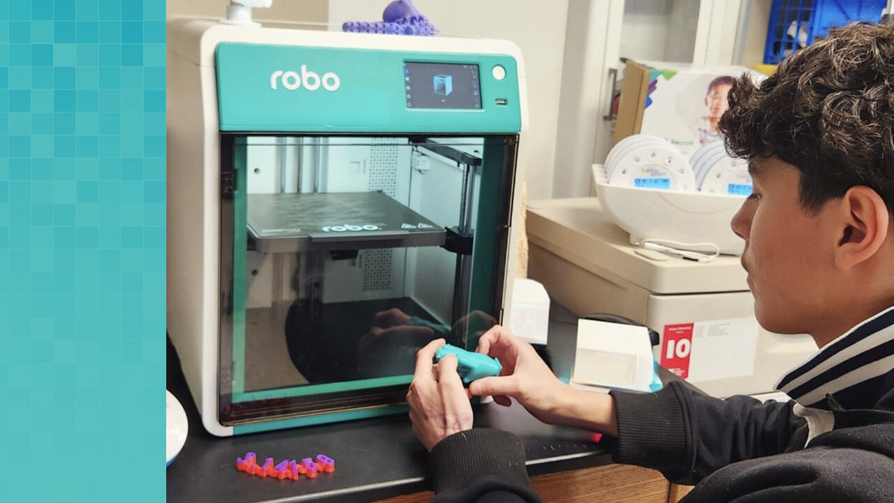 High school student holding a 3D printed ape next to Robo 3D printer.